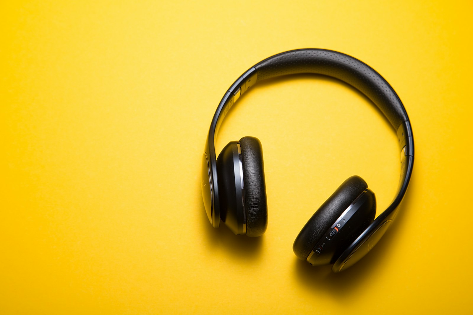 Black over-ear headphones with a wrapped headband on yellow